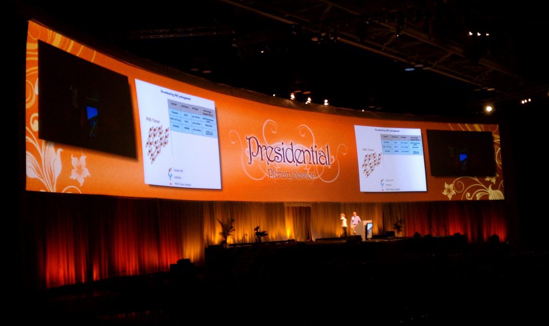 A curved video screen reading 'Presidential Plenary Session' above a lit stage.