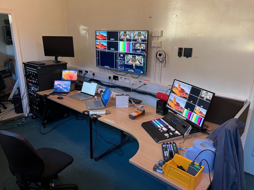 A broadcast control desk with multiview monitors, a vision mixer, and routing equipment.